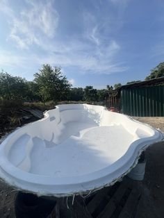 a large white bowl sitting on top of a wooden pallet in the middle of a dirt field