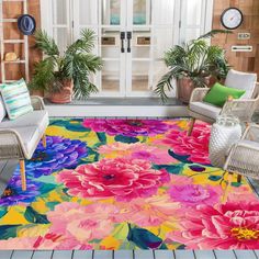 a colorful area rug with flowers on the floor and two chairs in front of it