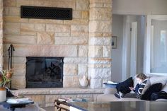 a young boy sitting on a couch in front of a fire place next to a table