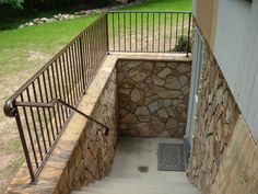 an outdoor stair case with stone walls and metal railings on the side of a house