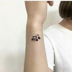 a small panda bear tattoo on the wrist