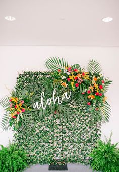 the wedding sign is surrounded by greenery and tropical flowers, which are arranged on top of each other