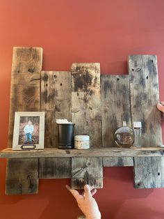 a person is pointing at a shelf made out of wooden planks with pictures on it