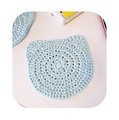 a blue crocheted pot holder sitting on top of a white table next to a book