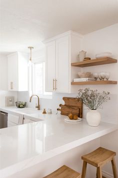 a kitchen with white counter tops and wooden stools