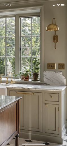 a kitchen with marble counter tops and gold fixtures on the windowsill, along with an island