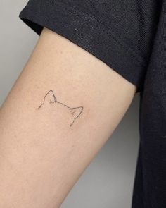 a woman's arm with a small cat tattoo on the left side of her arm