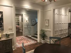 a living room filled with furniture next to a wooden table and white cabinets on top of a hard wood floor