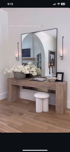 a large mirror sitting on top of a wooden table next to a vase filled with flowers