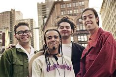 four young men standing together in the city