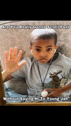 a young boy sitting in a chair with headphones on and his hand up to the camera