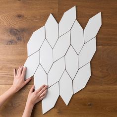 someone is making an origami fish out of paper on the floor with their hands