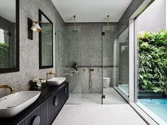 a bathroom with two sinks, mirrors and a walk in shower next to a swimming pool