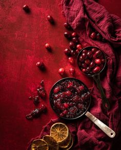 cranberry sauce and orange slices on a red cloth with spoons next to it