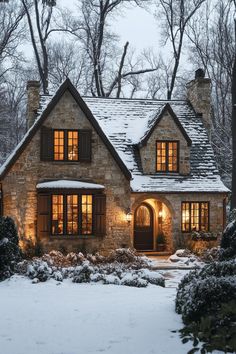 a stone house is lit up at night in the winter with snow on the ground