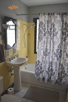 a bath room with a toilet a sink and a shower curtain next to a tub