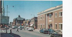 an old photo of cars driving down the street