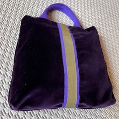 a purple and gold purse sitting on top of a white carpet