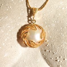 An ethereal 14k filigree mabe pearl pendant with an iridescent mother of pearl backing. The pearl cabochon has a lustrous reflection and sits inside an open back setting framed with a beautiful leaf overlay and suspended from a matching filigree bail. It looks like the mother of pearl cabochon has been glued to the back of the mabe pearl cabochon and is secured with gold prong clamps. Unfortunately one of the four prongs has broken off (see photos), but the pearl remains secure with only minimal Gold Pearl Necklace With High Luster Round Pendant, Exquisite Gold Jewelry With Mother Of Pearl, Luxury Gold Pearl Necklace In Mother Of Pearl, Luxury Gold Mother Of Pearl Necklace, Gold Pearl Necklace With Medallion Pendant, Gold Pearl Pendant Necklace In Medallion Shape, Gold Medallion Pearl Necklace With Pendant, Elegant Pearl Pendant Medallion Jewelry, Elegant Yellow Gold Mother Of Pearl Necklace