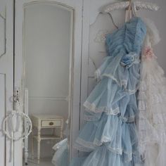 there is a dress hanging on the wall in front of a mirror and an open door