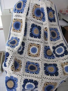 a crocheted blanket with blue and brown flowers on it sitting on top of a table