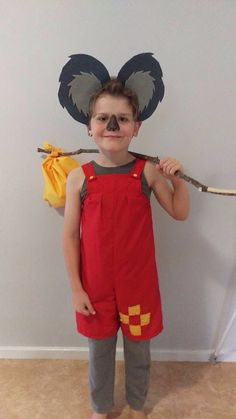 a young boy wearing mickey mouse ears and holding a stick