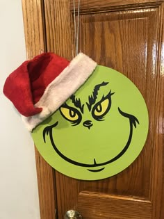 a grin face hanging on a door with a santa's hat on top of it