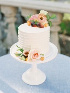 there is a white cake with flowers on the top and bottom, sitting on a table