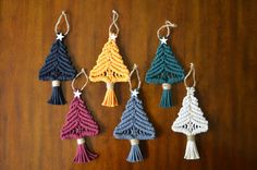 crocheted christmas tree ornaments hanging from strings on a wooden table with star decorations