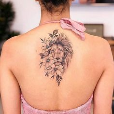 a woman's back with a lion and flowers tattoo on her left upper arm