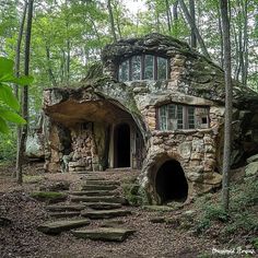 a stone house in the woods with steps leading up to it and a cave entrance