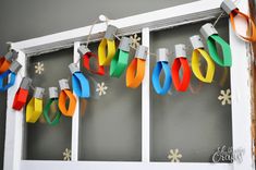 an old window is decorated with christmas lights and paper streamers on the windowsill