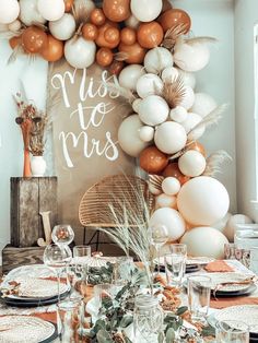 the table is set with plates, silverware and white balloons that read miss to mrs