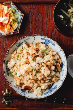 a bowl filled with rice and vegetables on top of a wooden table