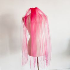 a mannequin wearing a pink veil on top of it's head in front of a white wall