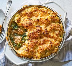 a casserole dish with meat and vegetables in it on a white plate next to a spoon