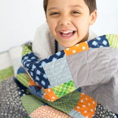 a young boy is smiling while holding a quilt