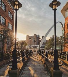 the sun is setting on an urban street with tall buildings and lampposts in the foreground