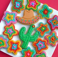 decorated cookies are arranged in the shape of flowers and a cactus on a white plate