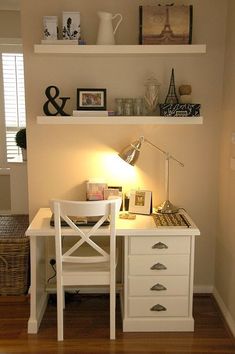 a white desk with a lamp on top of it next to a wall mounted shelf