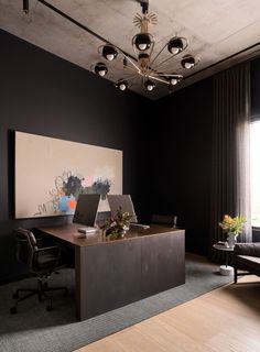 an office with a desk, chair and large painting on the wall