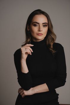 a woman posing for the camera with her hand on her chin and wearing a black turtle neck sweater