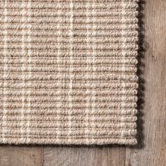 an area rug on top of a wooden floor with a white and beige color scheme