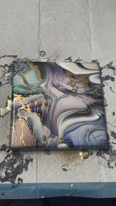 a piece of art sitting on top of a table next to a metal object with gold and blue designs