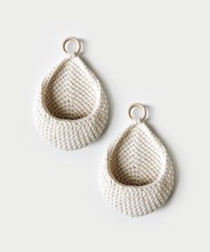 two white crocheted earrings on a white background, one is hanging from the side