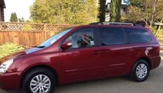 a red minivan parked in front of a wooden fence