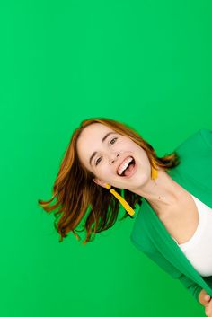 a woman is smiling while holding a toothbrush in her mouth and wearing a green jacket