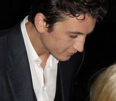 a close up of a person in a suit and tie looking down at his cell phone