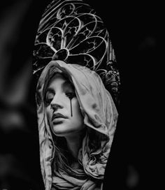 a black and white photo of a woman's face with her head covered by a veil