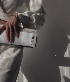 a woman in white dress holding a purse with the word dior written on it